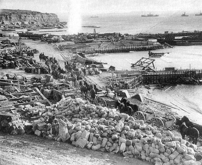 A series of hastily constructed piers and men on the beach at Cape Helles, Gallipoli.